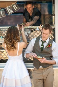 En la imagen aparecen dos recién casados comiendo en el food truck, rompen con lo cotidiano y con este camión de comida suplen el banquete de la boda.